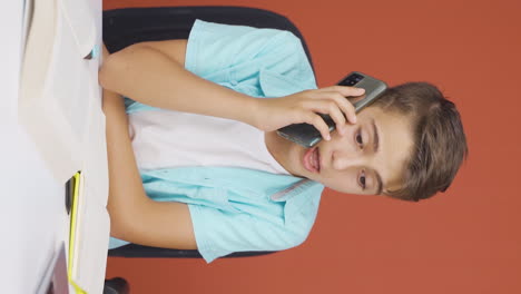 Video-Vertical-De-Un-Niño-Usando-Una-Computadora-Portátil-Hablando-Nerviosamente-Por-Teléfono.